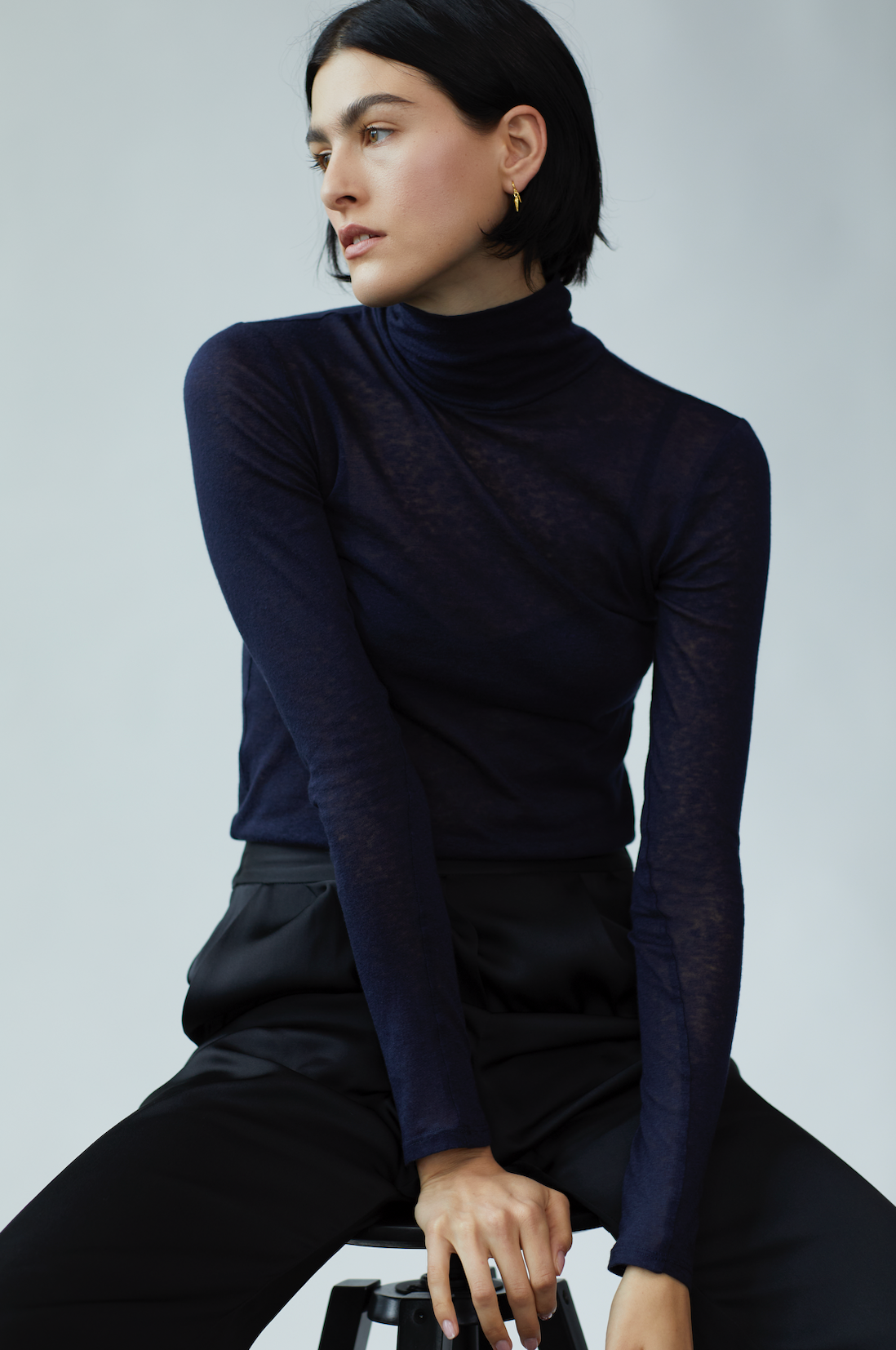 Model sits on a stool wears i seira pod drop earrings in collaboration with brand, frances de lourdes