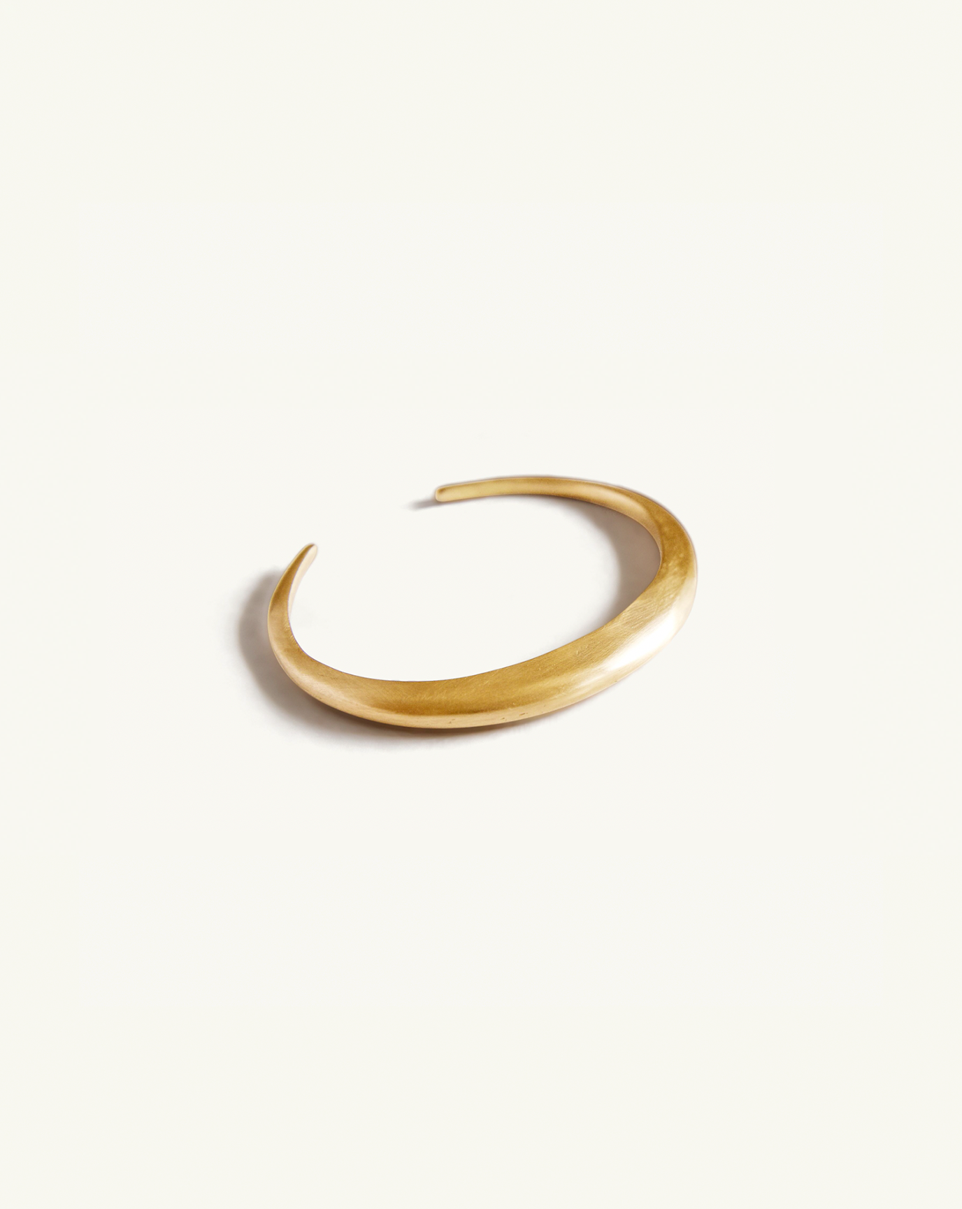 Product image of the open gold bangle on flat surface