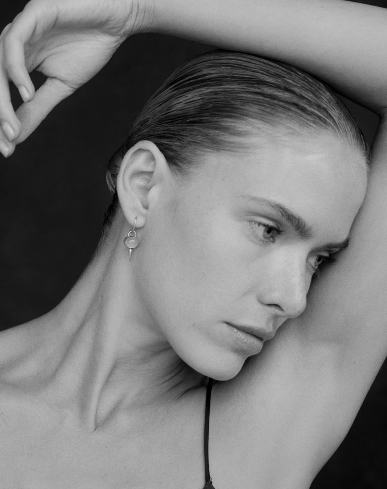 Black and white image of i seira model wearing the gemstone drops in aquamarine as she raises her arm above her head