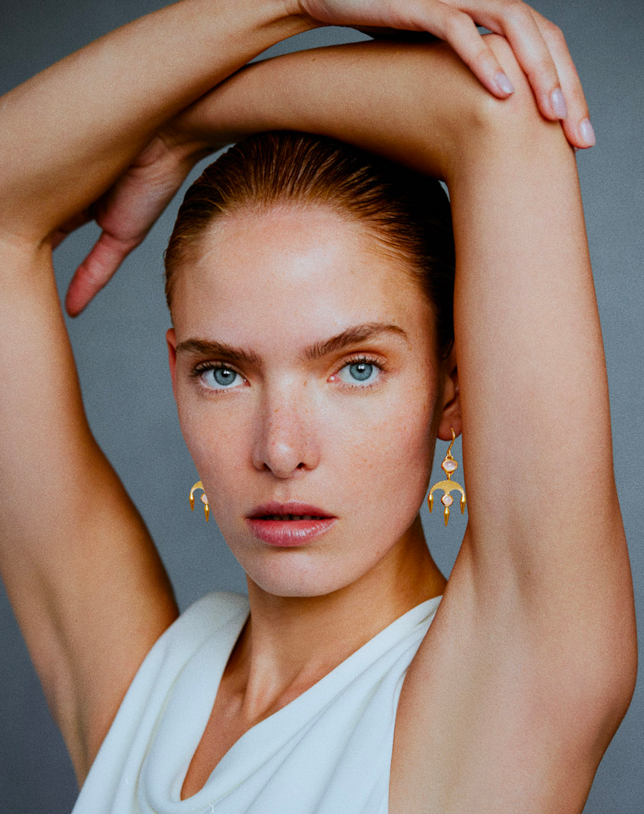 Image of i seira model wearing the chandelier white moonstone earrings with her arms raised above her head
