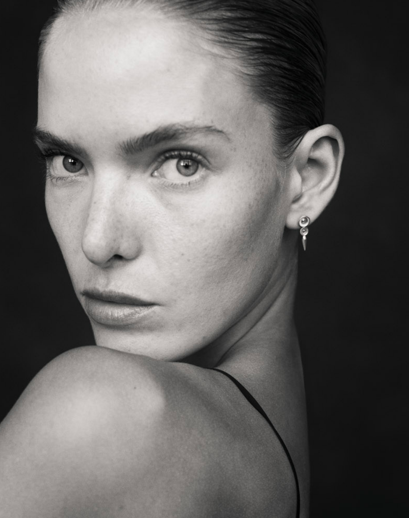 Black and white close up image of i seira model wearing the concave pod studs as she looks over her shoulder
