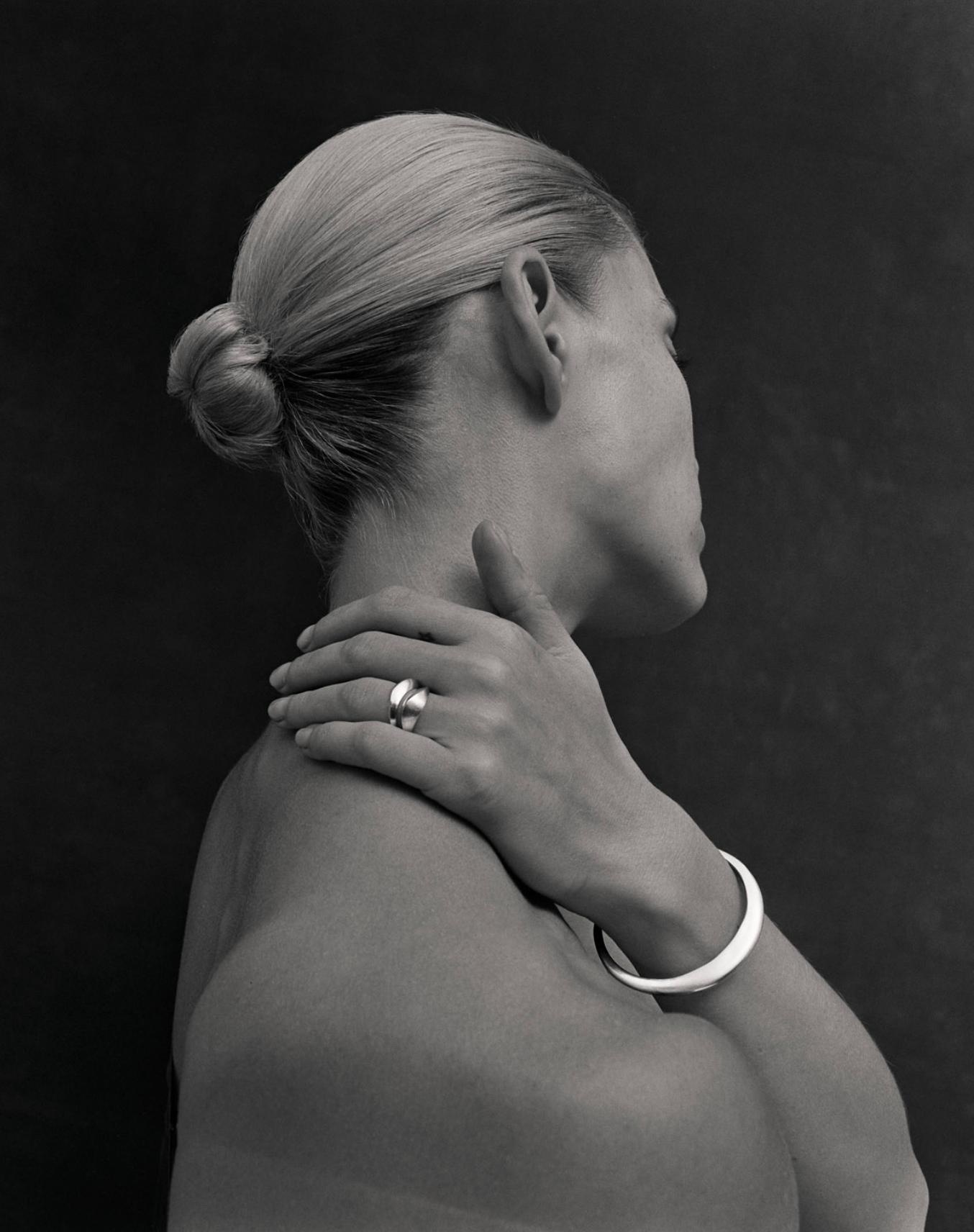Black and white close up image of i seira model with her arm over her shoulder, wearing the oval bangle and sculptural rings