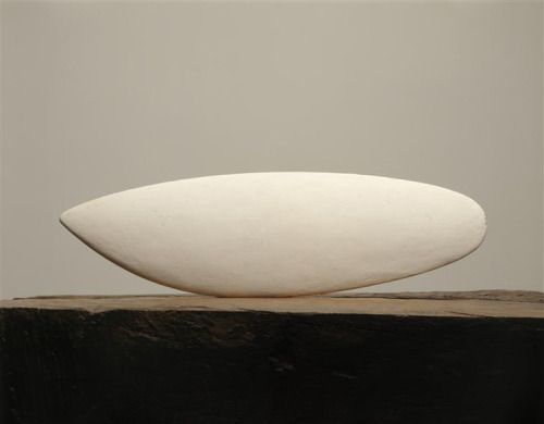 Reference image of an oval clay sculpture on a stone table.