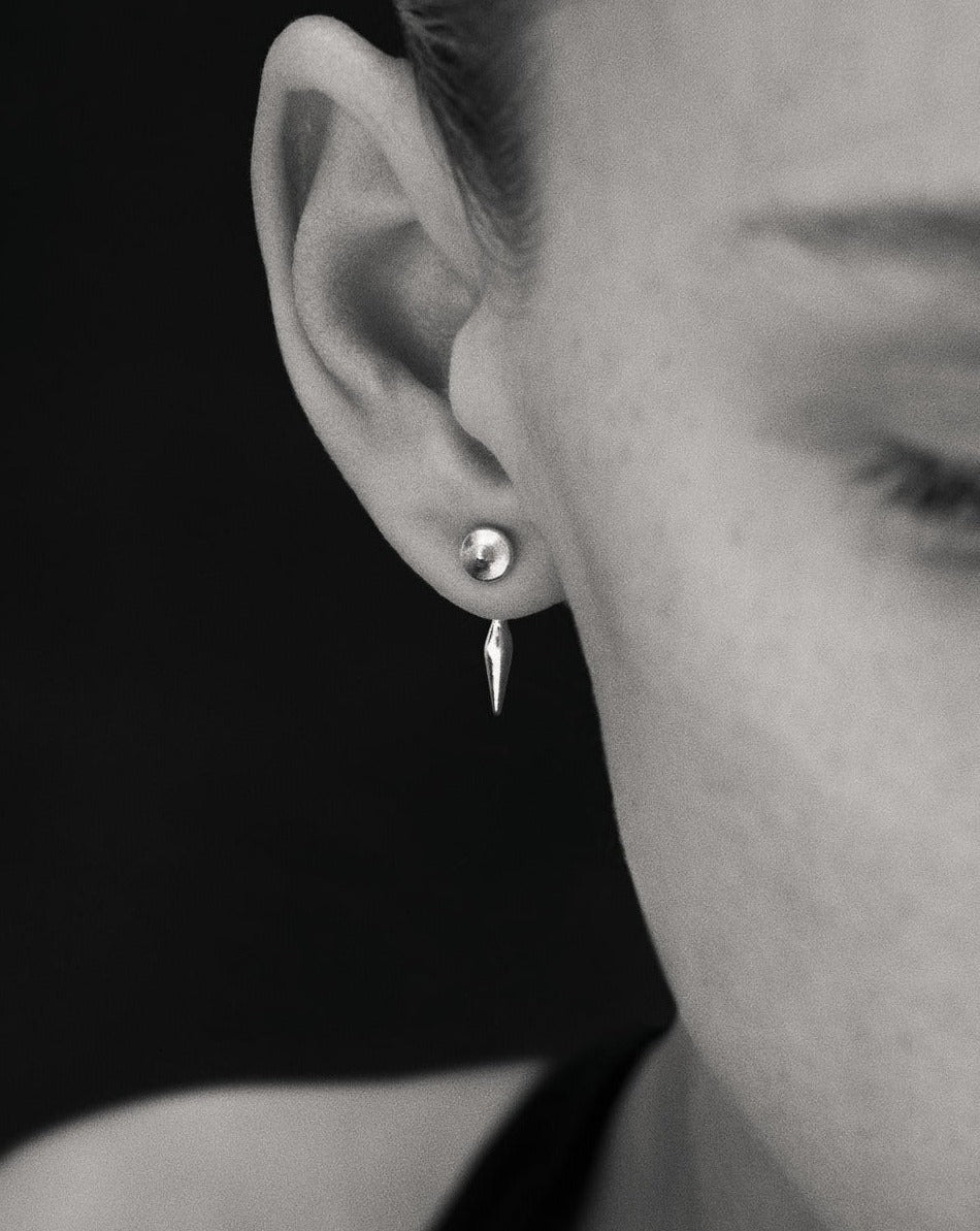 Black and white close up image of model wearing gold stud earrings