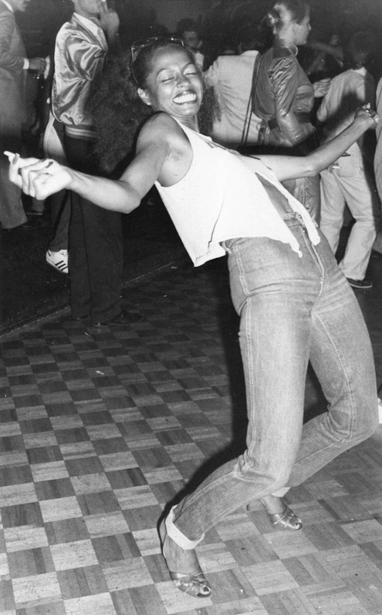 Black and white image of Diana Ross smiling and dancing in a club