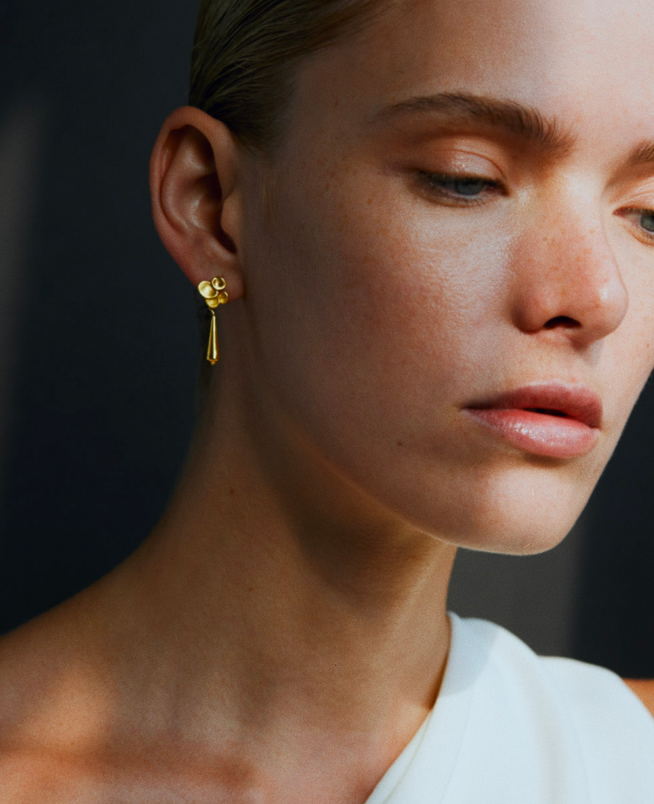 i seira model wearing the gold tapered drop earrings in gold