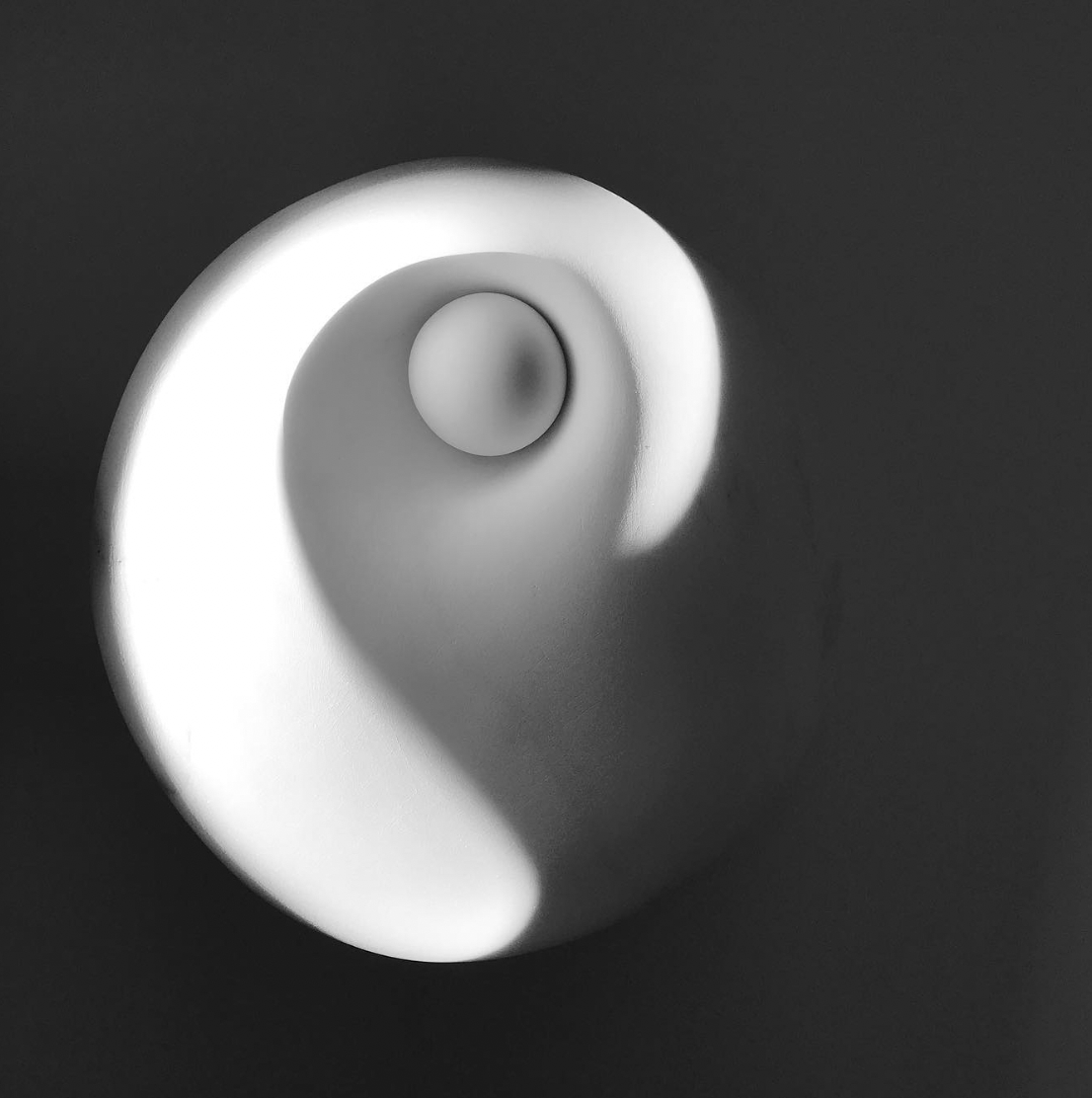 Black and white image of a small ceramic ball and vase sculpture