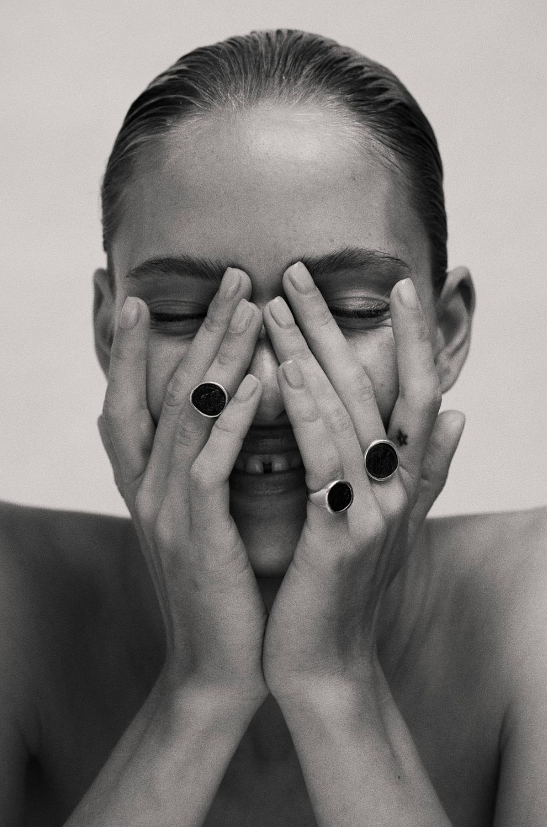 Model wears three i seira statement rings and has her hands over her eyes.