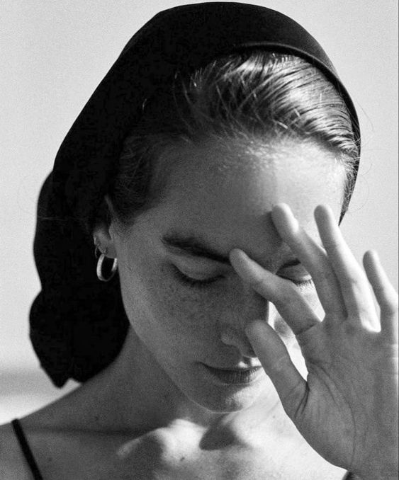 Black and white image of a model wearing a black headscarf in the sun.