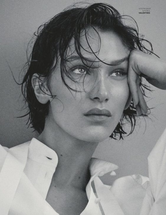 Black and white image of Bella Hadid in a white shirt with short hair.