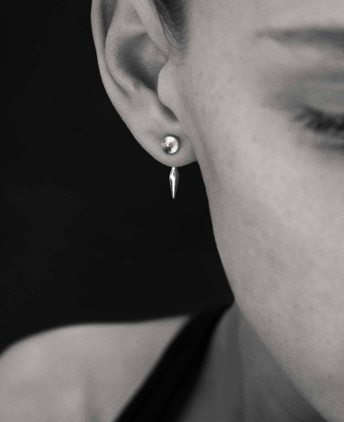 Black and white close up image of i seira model wearing the pod studs