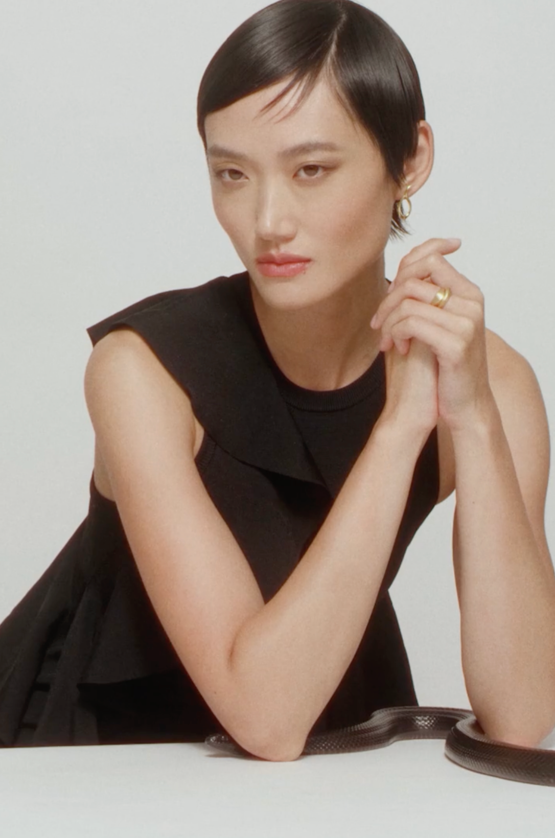 Model wears i seira gold earrings and sculptural ring with a snake on her arms.