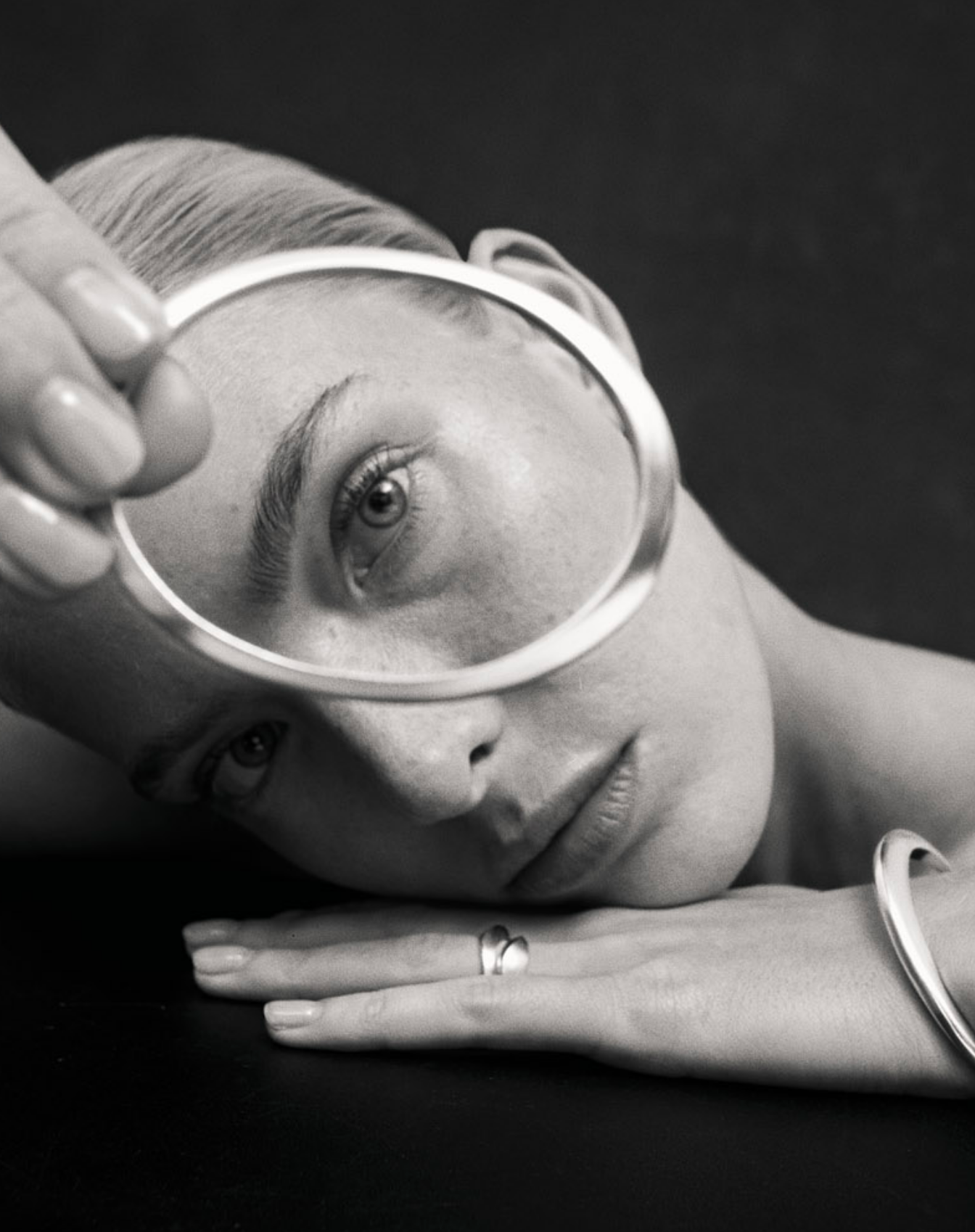 Black and white close up image of i seira model looking through the oval bangle